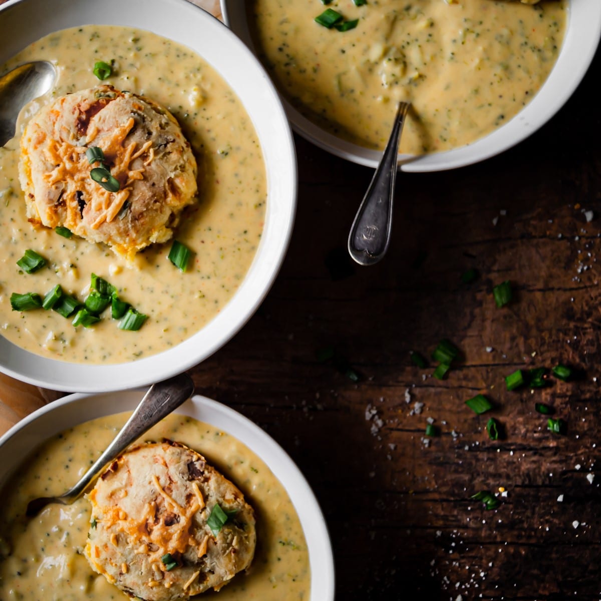 Creamy broccoli cheddar cheese soup in bowls topped with a biscuit