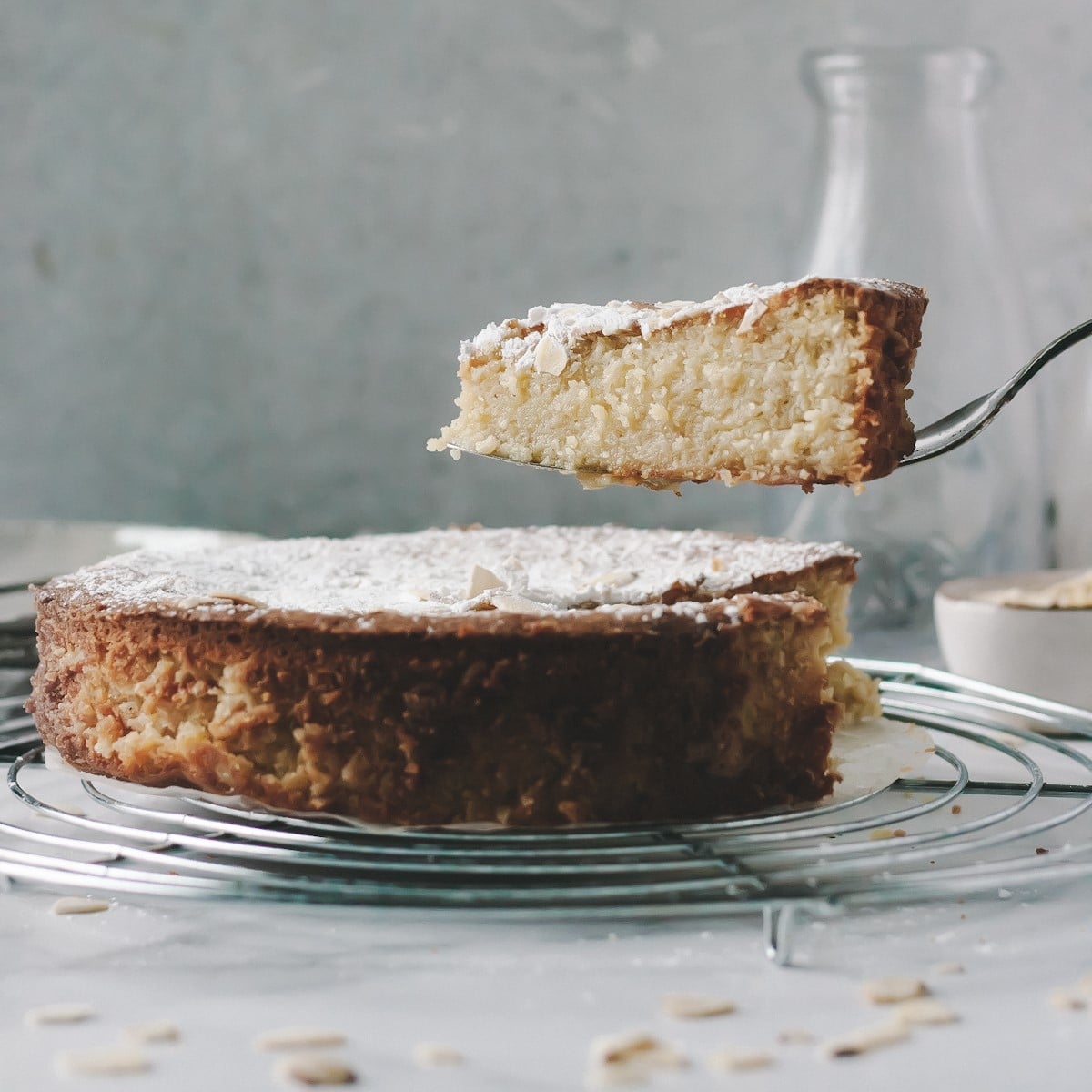 slice of gluten free lemon ricotta cake with almond flour being served from a whole cake