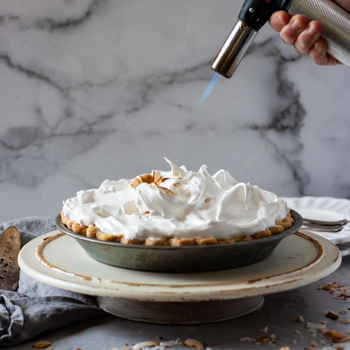 marshmallow meringue being toasted on coconut cream pie