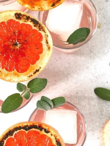 Overhead view of a grapefruit gin cocktail in a glass with bruleed grapefruit garnish.
