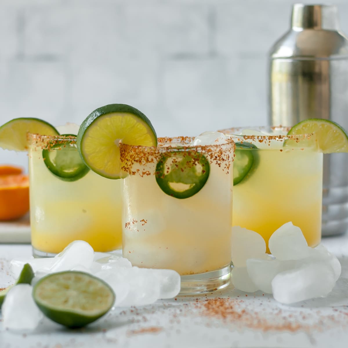 three margaritas in glasses with jalapeno and lime