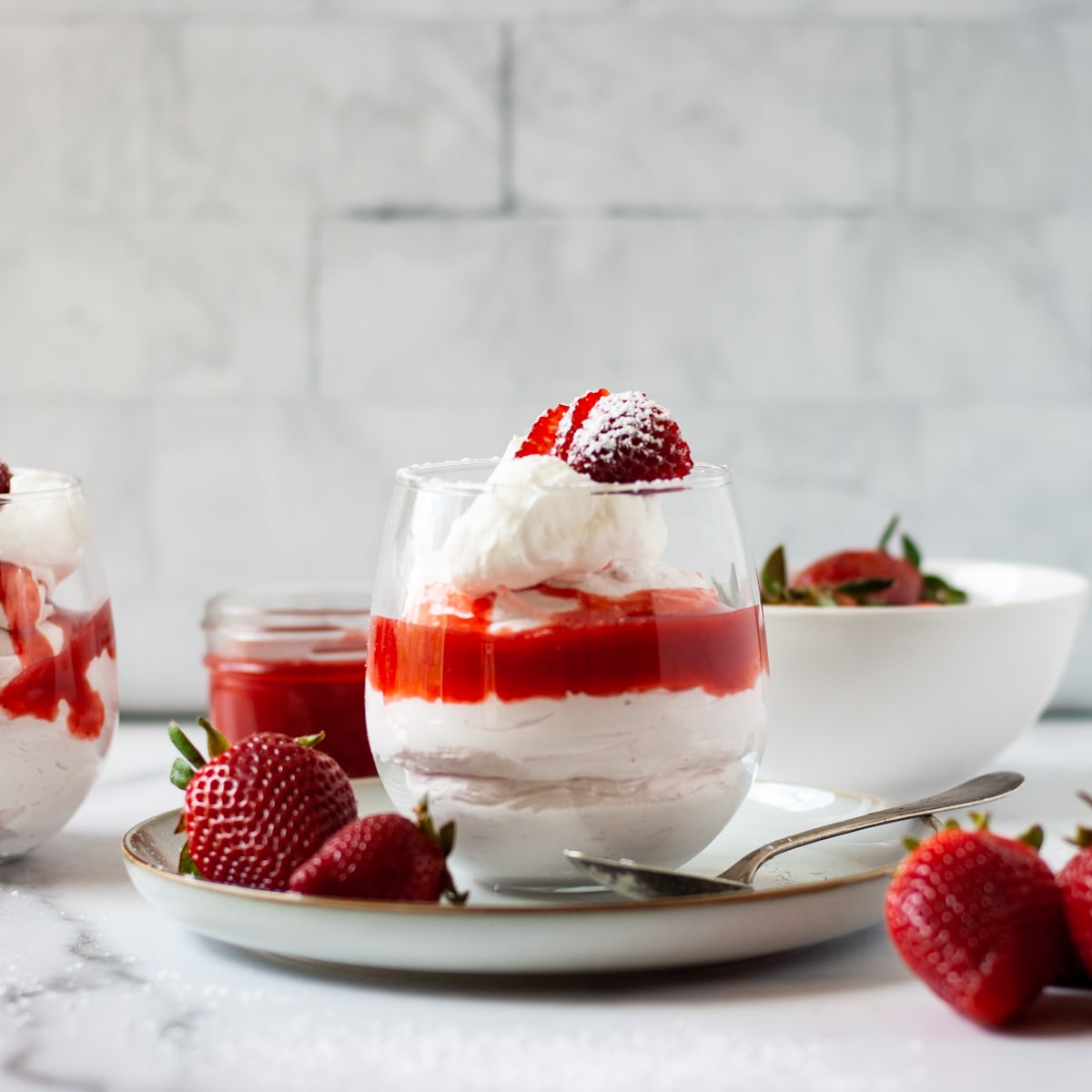 Strawberry mousse in a glass with strawberries and whipped cream.