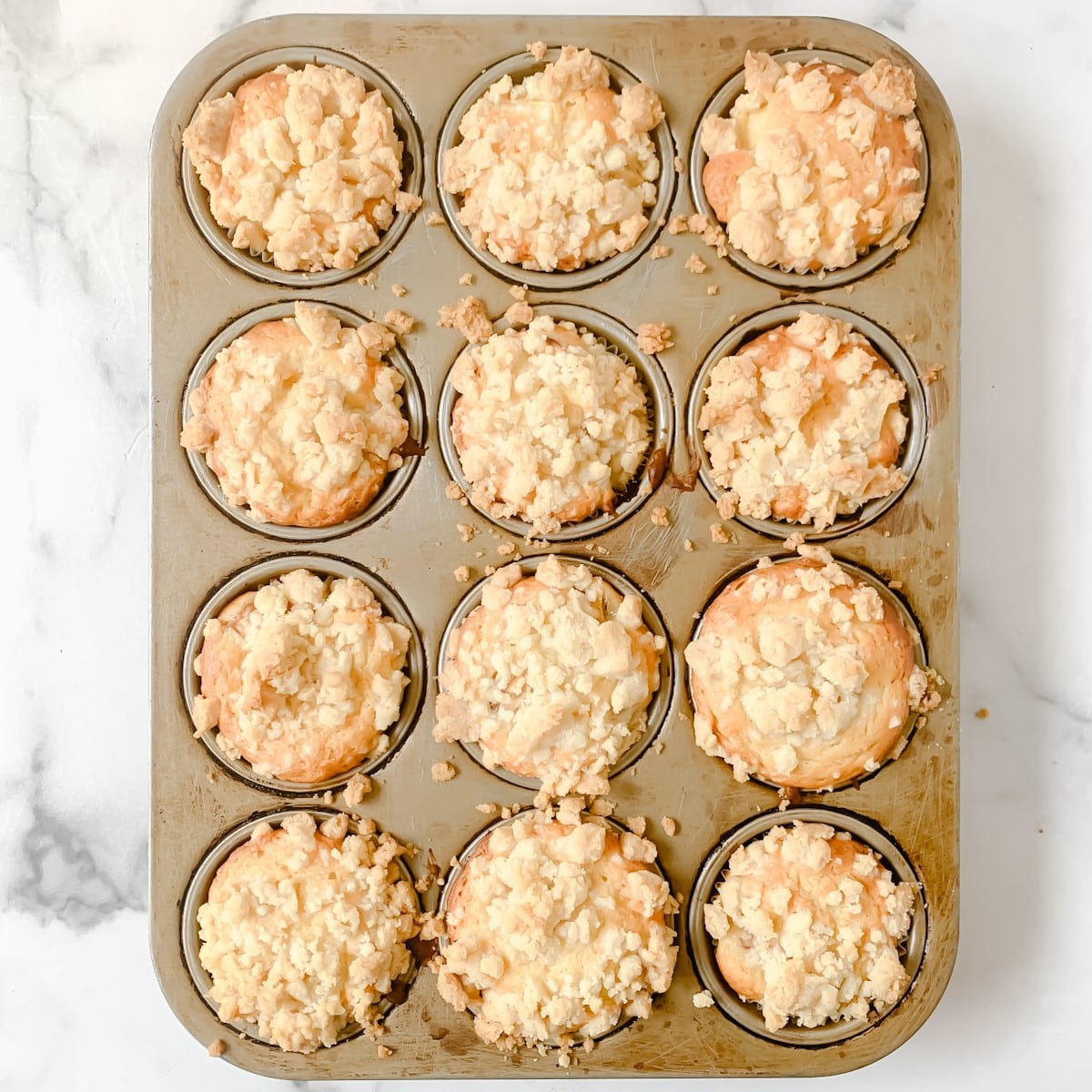 Baked peach muffins in a muffin pan.