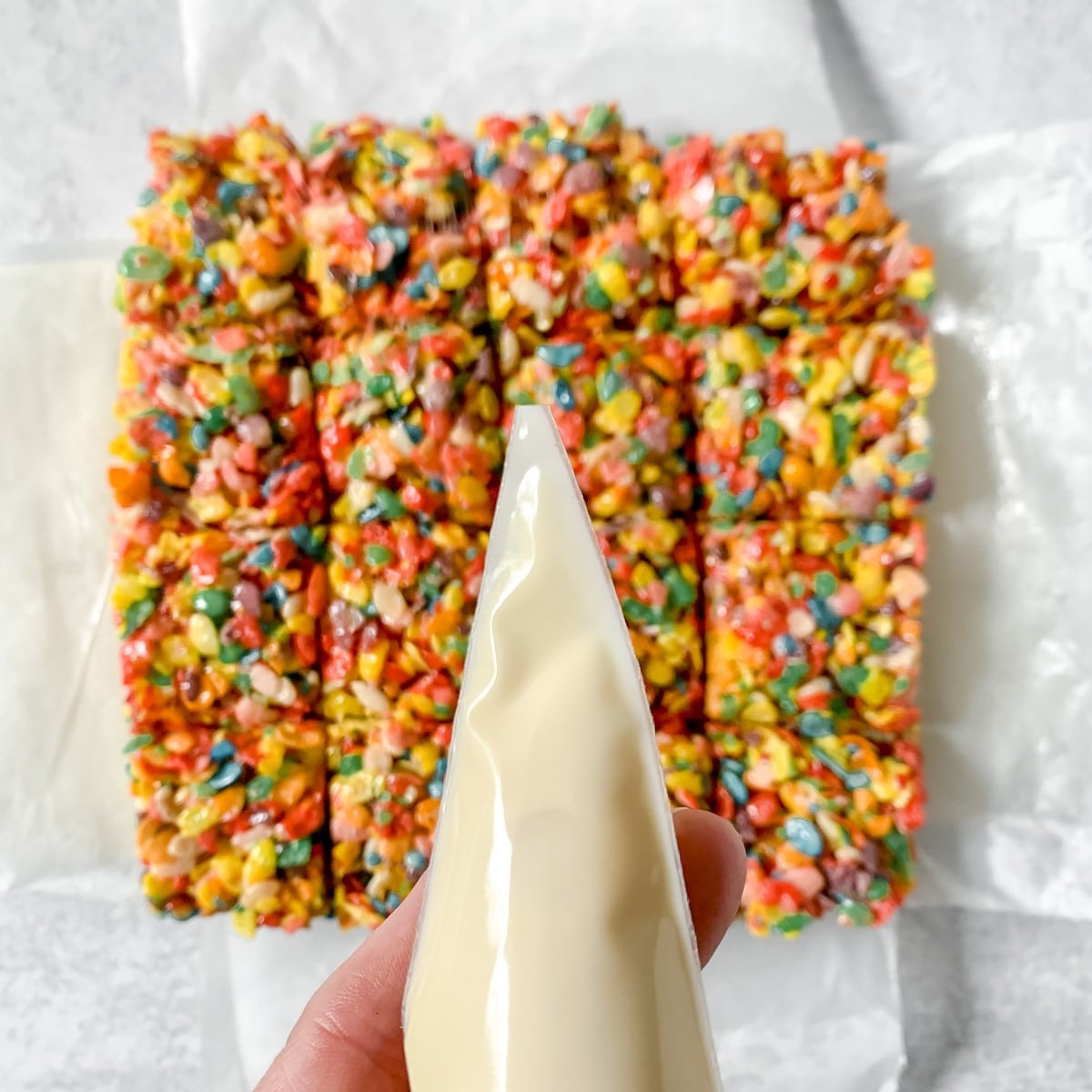 Fruity pebbles bars and melted white chocolate glaze in a piping bag.